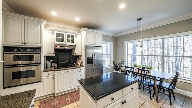 kitchen with under cabinet range hood, white cabinets, appliances with stainless steel finishes, decorative backsplash, and crown molding