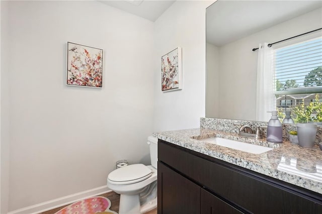 half bathroom featuring baseboards, vanity, and toilet