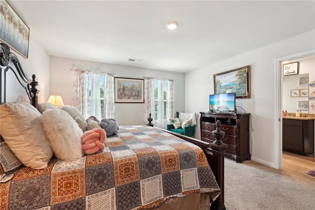 bedroom with light carpet, ensuite bath, visible vents, and baseboards