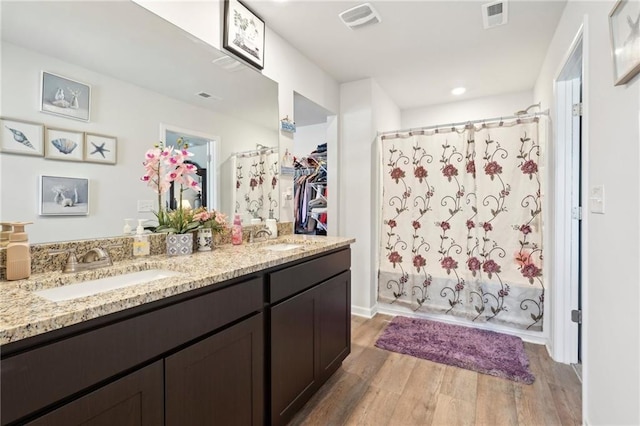 bathroom with a shower with curtain, visible vents, a sink, and wood finished floors