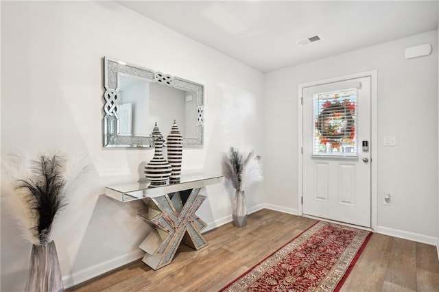 foyer with wood finished floors, visible vents, and baseboards