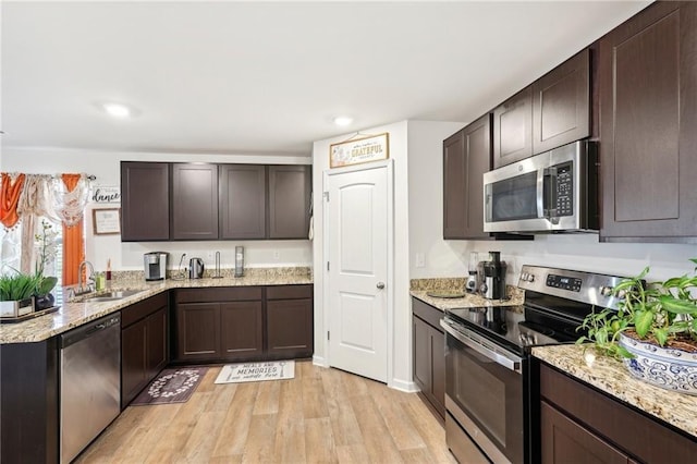 kitchen featuring light wood-style flooring, appliances with stainless steel finishes, dark brown cabinets, and a sink