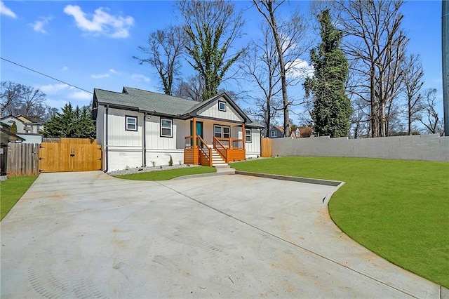 view of front of home with a gate, fence, roof with shingles, board and batten siding, and a front yard