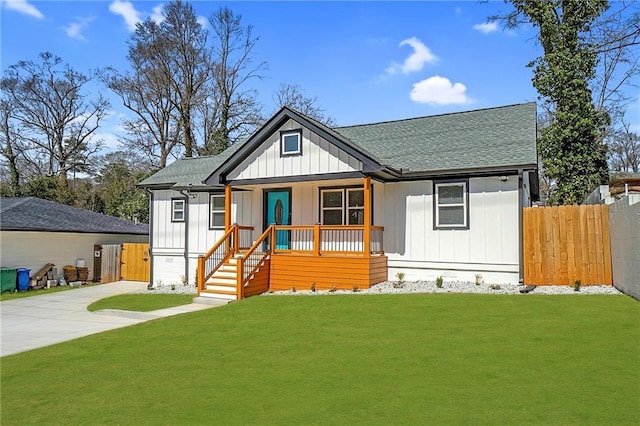 modern farmhouse style home featuring a porch, a shingled roof, a front yard, and fence