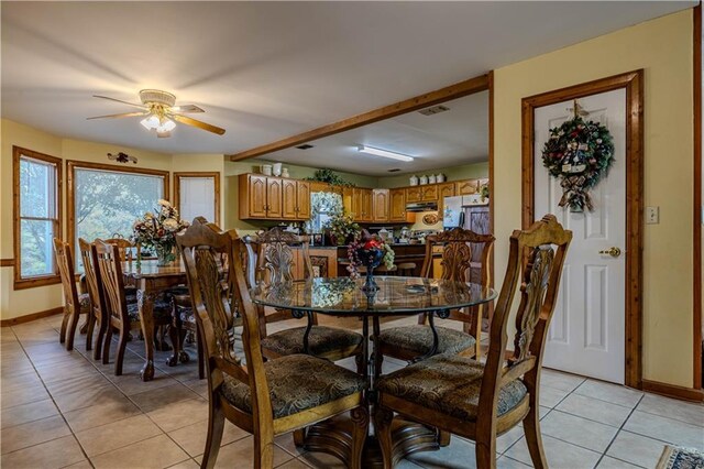 kitchen featuring light tile patterned flooring, beam ceiling, appliances with stainless steel finishes, and a breakfast bar