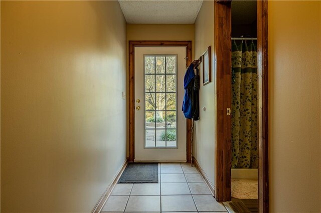 hallway with a textured ceiling and light tile patterned floors