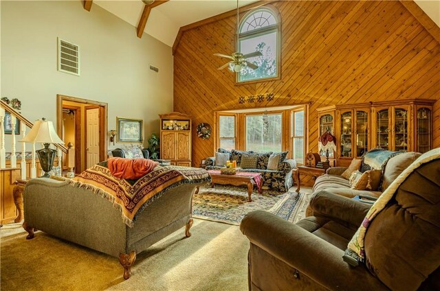 living room with light carpet, ceiling fan, high vaulted ceiling, wood walls, and beamed ceiling