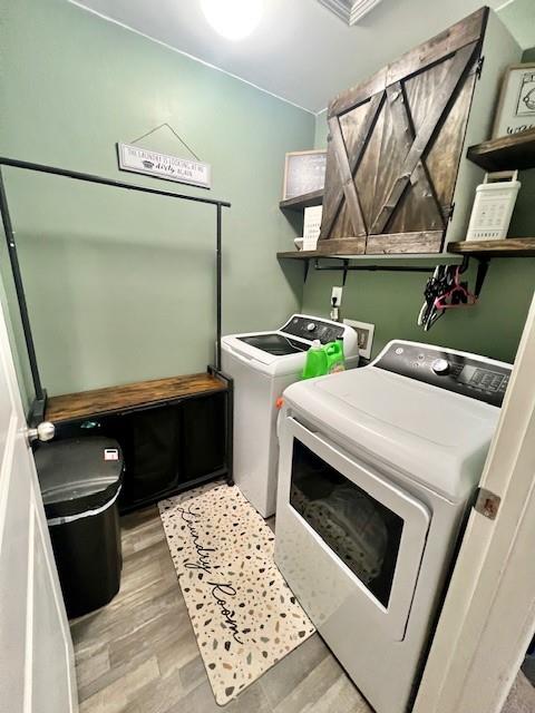 laundry area with light hardwood / wood-style floors and washer and dryer