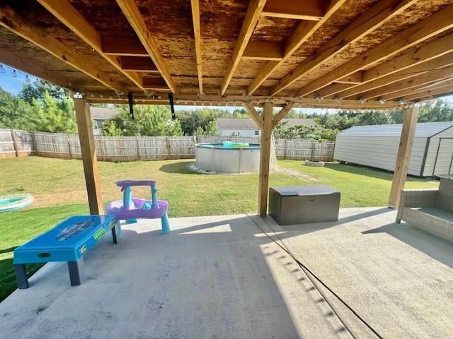 view of patio / terrace featuring a fenced in pool and a shed