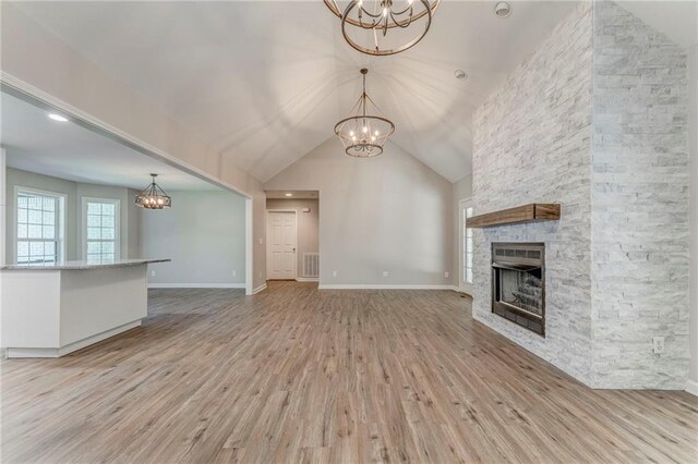 14 Brook Valley Ct SW, Rome, GA 30165 - unfurnished living room with a chandelier, light wood finished floors, a stone fireplace, lofted ceiling, and baseboards