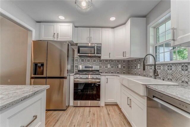 14 Brook Valley Ct SW, Rome, GA 30165 - kitchen with stainless steel appliances, white cabinetry, light wood-style flooring, decorative backsplash, and a sink