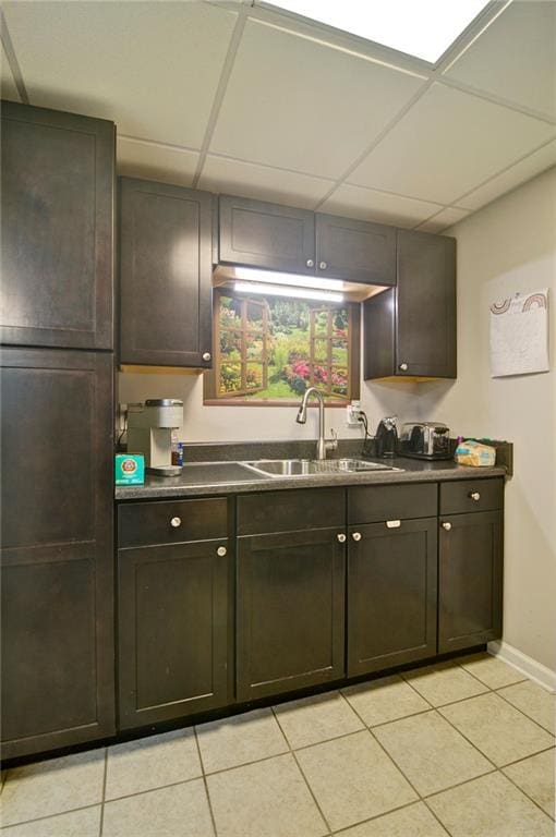 809 Longbranch Ln, Douglasville, GA 30134 - kitchen featuring a sink, light tile patterned floors, dark countertops, baseboards, and a paneled ceiling