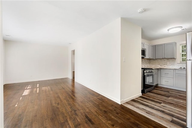 kitchen featuring gray cabinetry, light stone counters, dark hardwood / wood-style flooring, and stainless steel appliances