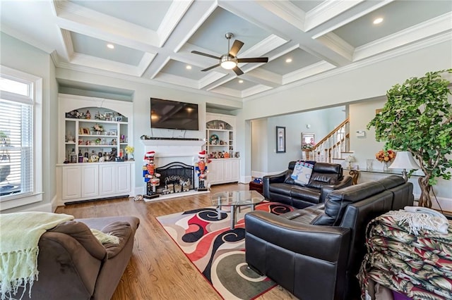 living room featuring ceiling fan, light hardwood / wood-style flooring, ornamental molding, beamed ceiling, and coffered ceiling