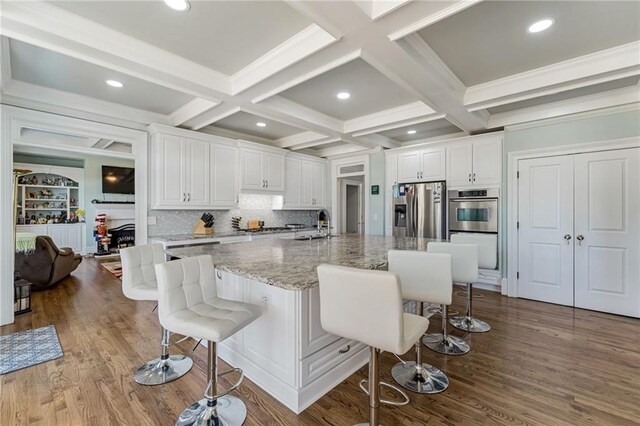 kitchen featuring a kitchen breakfast bar, white cabinets, a large island with sink, and stainless steel fridge with ice dispenser