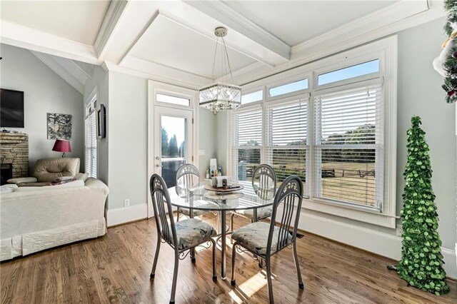 dining room featuring hardwood / wood-style floors, beam ceiling, ornamental molding, a stone fireplace, and a notable chandelier