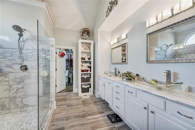 bathroom with vanity, hardwood / wood-style floors, a tile shower, and crown molding