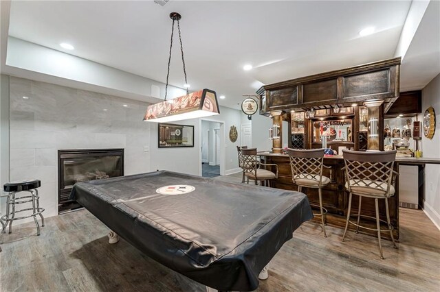 playroom with a tile fireplace, billiards, indoor bar, and light wood-type flooring