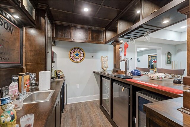 kitchen with hardwood / wood-style flooring, dark brown cabinetry, sink, and stainless steel fridge