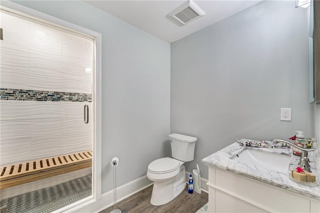 bathroom with a shower with door, vanity, wood-type flooring, and toilet