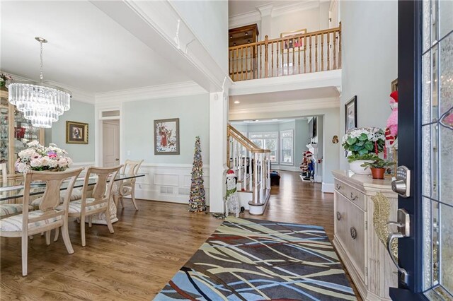 foyer entrance featuring ornamental molding, a high ceiling, dark hardwood / wood-style floors, and a chandelier