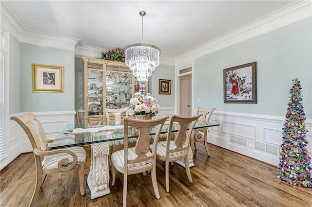 dining area with ornamental molding, a notable chandelier, and hardwood / wood-style floors