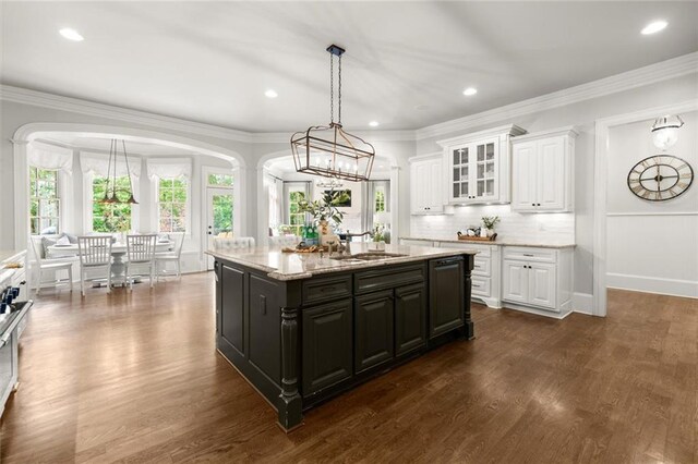 15910 Meadow King Way, Milton, GA 30004 - kitchen featuring white cabinets, dark wood-style floors, a kitchen island with sink, glass insert cabinets, and ornamental molding