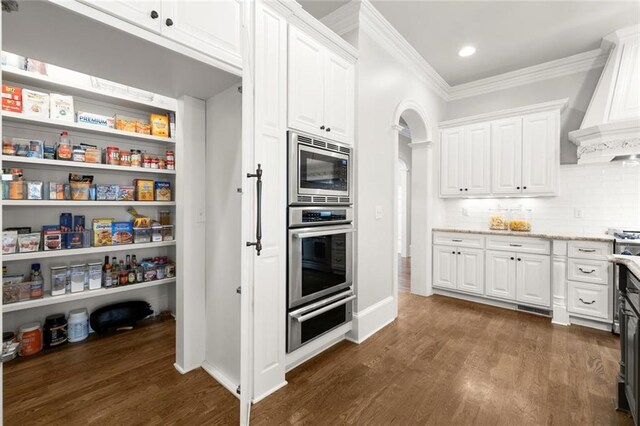 15910 Meadow King Way, Milton, GA 30004 - kitchen featuring stainless steel appliances, custom range hood, a warming drawer, crown molding, and dark wood-type flooring