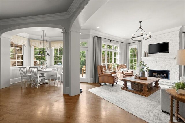 15910 Meadow King Way, Milton, GA 30004 - living area with a chandelier, wood finished floors, a large fireplace, crown molding, and arched walkways