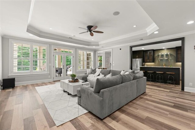 15910 Meadow King Way, Milton, GA 30004 - living area with a raised ceiling, a ceiling fan, light wood-style floors, crown molding, and bar area