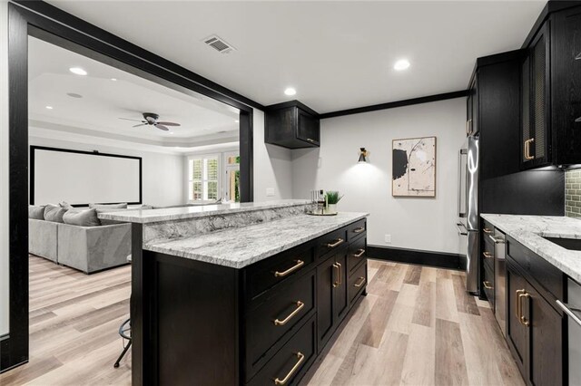 15910 Meadow King Way, Milton, GA 30004 - kitchen with dark cabinets, crown molding, light wood-style floors, a kitchen bar, and light stone counters