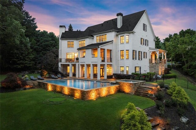 15910 Meadow King Way, Milton, GA 30004 - back of property at dusk with a jacuzzi, a chimney, an outdoor pool, stairs, and a balcony