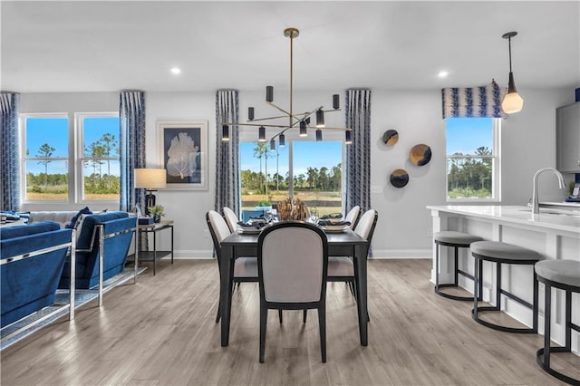 dining area with a chandelier, baseboards, light wood-style flooring, and recessed lighting