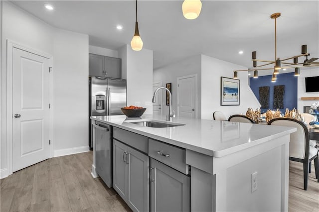 kitchen featuring a sink, gray cabinetry, appliances with stainless steel finishes, a chandelier, and light wood finished floors
