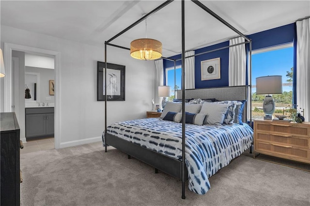 carpeted bedroom featuring multiple windows, a sink, baseboards, and connected bathroom