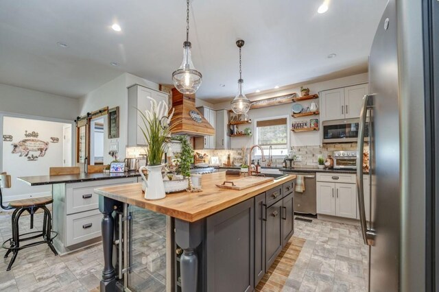 kitchen featuring stainless steel appliances, a barn door, butcher block counters, and a kitchen island