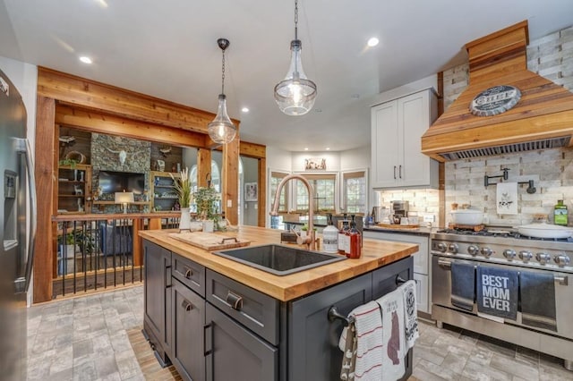 kitchen with sink, wooden counters, a center island, appliances with stainless steel finishes, and white cabinets