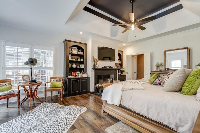 bedroom with a tray ceiling, dark wood-type flooring, ornamental molding, and ceiling fan