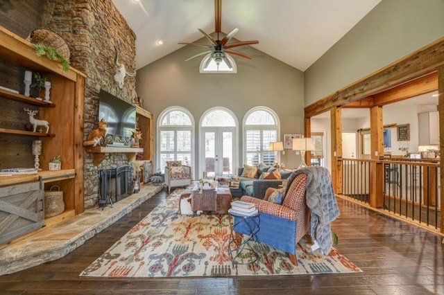 living room featuring high vaulted ceiling, a fireplace, dark hardwood / wood-style flooring, ceiling fan, and french doors