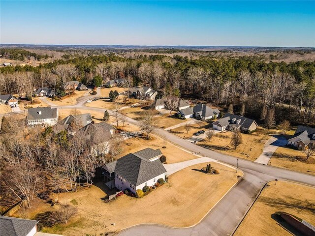 aerial view of property and surrounding area with nearby suburban area and a heavily wooded area