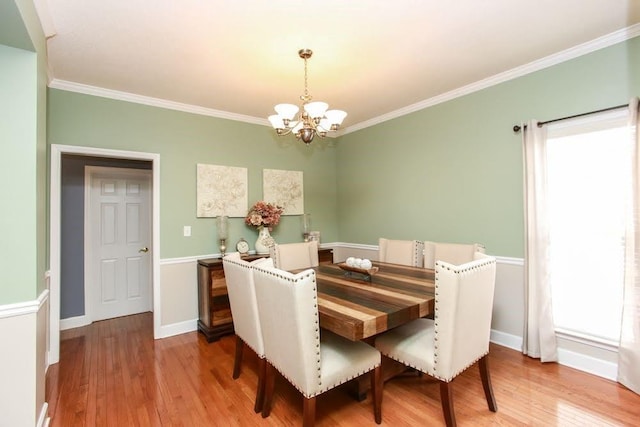 dining room with a chandelier, light wood-type flooring, ornamental molding, and baseboards