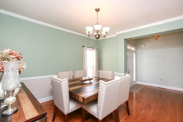 dining area with a chandelier, ornamental molding, baseboards, and wood finished floors