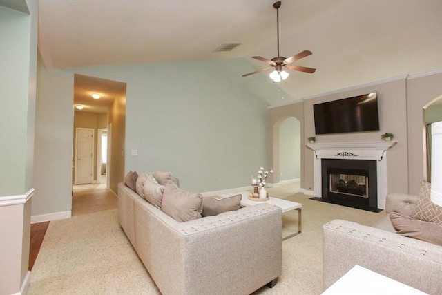 carpeted living room with arched walkways, a ceiling fan, lofted ceiling, a fireplace with flush hearth, and baseboards