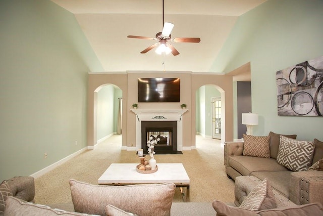 living area with arched walkways, vaulted ceiling, a ceiling fan, light carpet, and baseboards