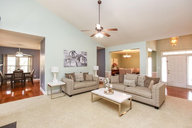 living area featuring a ceiling fan, wood finished floors, a chandelier, baseboards, and high vaulted ceiling