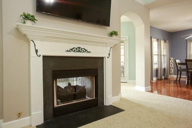 detailed view of a multi sided fireplace, arched walkways, carpet flooring, and baseboards