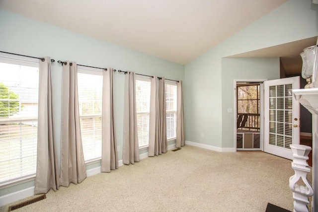 carpeted empty room featuring lofted ceiling, baseboards, and healthy amount of natural light