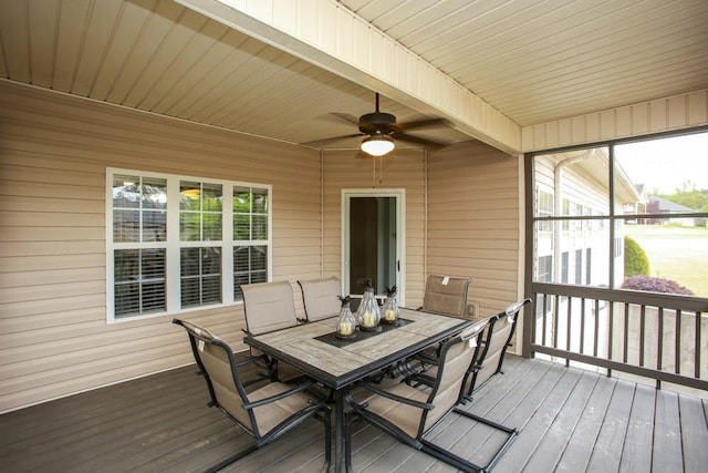wooden deck with outdoor dining area and a ceiling fan