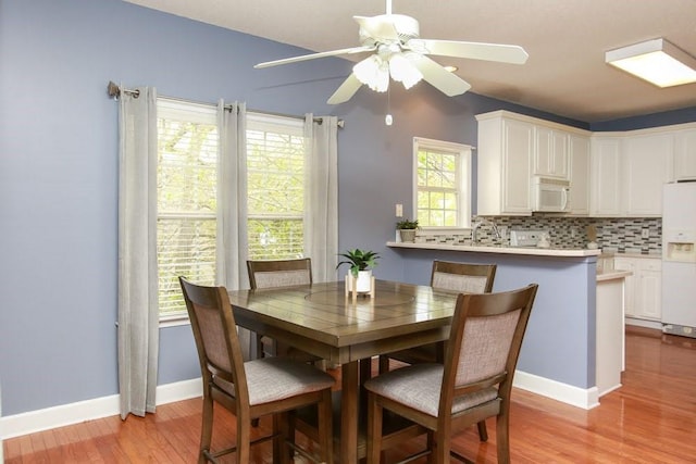 dining space featuring a ceiling fan, light wood-type flooring, and baseboards