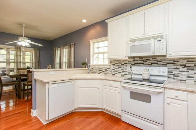 kitchen with white appliances, a sink, light wood-style floors, tasteful backsplash, and recessed lighting